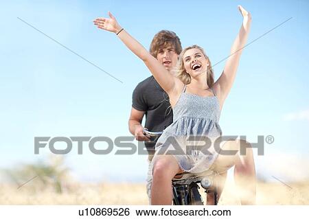 Stock Photograph - Couple riding bicycle in tall grass. Fotosearch