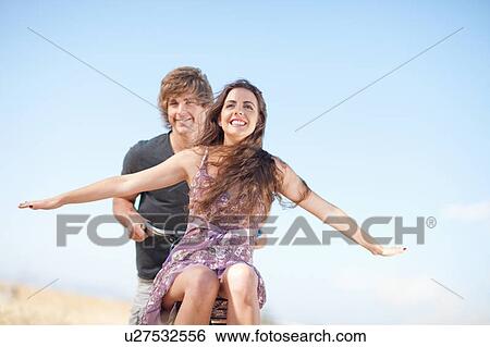 Stock Photograph - Couple riding bicycle outdoors. Fotosearch