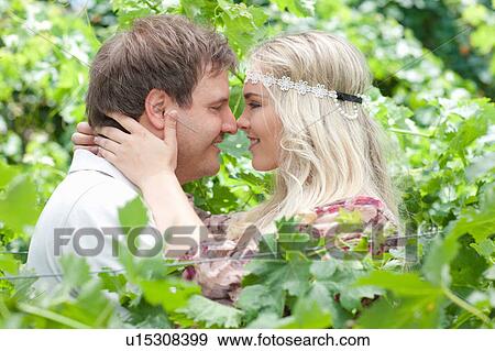 Couple touching noses in tall plants View Large Photo Image Stock Photo - Couple touching noses in tall plants. Fotosearch
