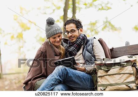 Couple using tablet computer in park View Large Photo Image Stock Photo - Couple using tablet computer in park. Fotosearch