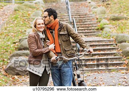 Couple walking bicycle in park View Large Photo Image Stock Photograph - Couple walking bicycle in park. Fotosearch