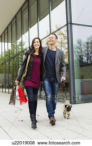 Couple walking dog on city street View Large Photo Image Stock Photo - Couple walking dog on city street. Fotosearch