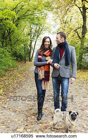 Stock Photography - Couple walking dog on dirt path. Fotosearch