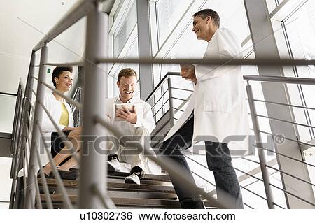 Stock Photograph - Doctors talking on steps in hospital. Fotosearch