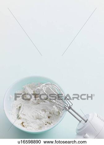 Stock Image - Electric mixer in bowl of frosting. Fotosearch