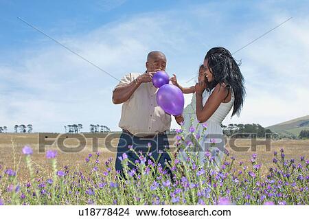 Picture - Family playing with balloons in field. Fotosearch
