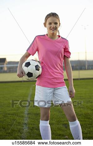 Picture - Football player holding ball in field. Fotosearch