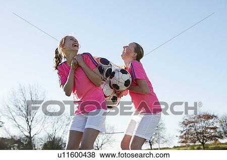 Stock Photo - Football players carrying balls in field. Fotosearch