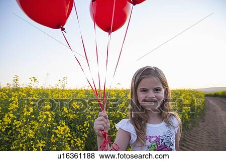 Girl carrying balloons on dirt road View Large Photo Image Stock Photo - Girl carrying balloons on dirt road. Fotosearch
