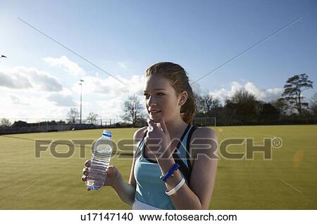 Stock Image - Girl drinking water in field. Fotosearch