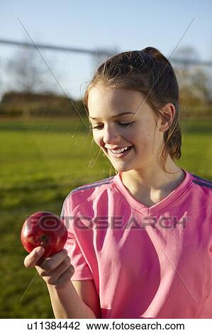 Stock Image - Girl eating apple in field. Fotosearch