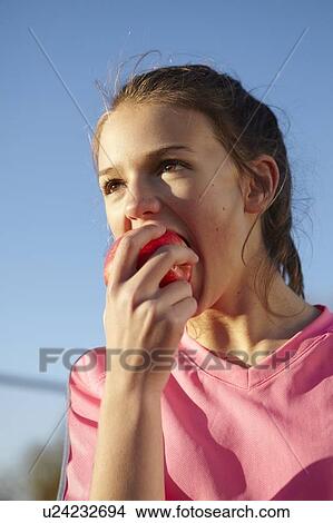 Girl eating apple outdoors View Large Photo Image Picture - Girl eating apple outdoors. Fotosearch