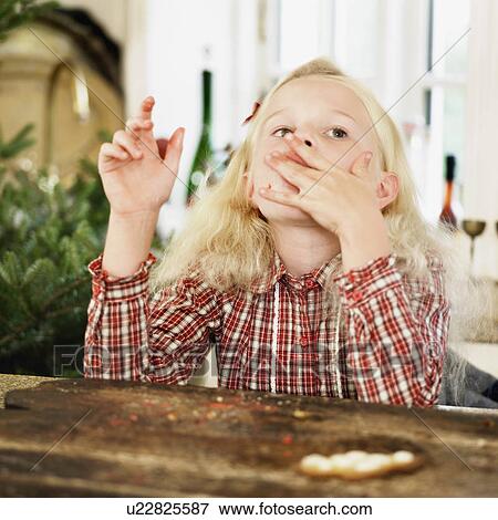 Girl eating Christmas cookies in kitchen View Large Photo Image Stock Photo - Girl eating Christmas cookies in kitchen. Fotosearch