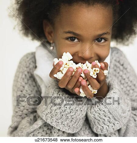 Stock Photo - Girl eating handful of popcorn. Fotosearch