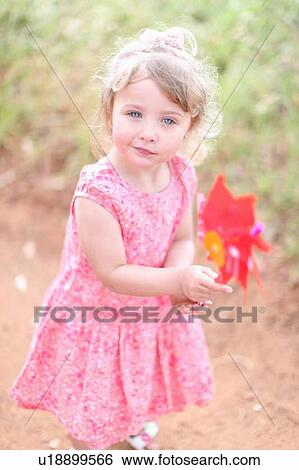 Girl holding pinwheel on dirt road View Large Photo Image Stock Photograph - Girl holding pinwheel on dirt road. Fotosearch