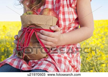 Stock Image - Girl holding sack of apples outdoors. Fotosearch