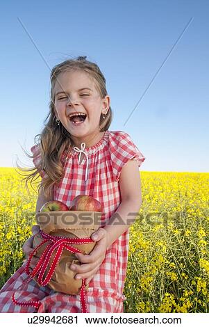 Stock Image - Girl holding sack of apples outdoors. Fotosearch