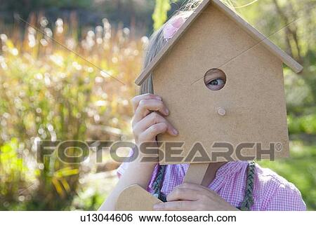 Stock Photograph - Girl peeking through birdhouse. Fotosearch