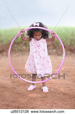 Stock Photo - Girl playing with hula hoop on dirt road. Fotosearch