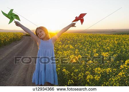 Stock Photograph - Girl playing with pinwheels outdoors. Fotosearch