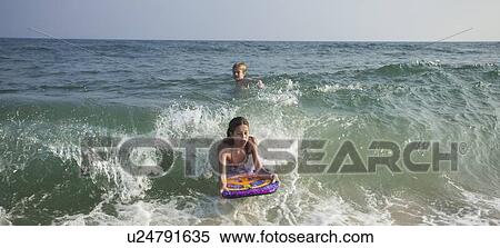 Girl riding wave on boogie board View Large Photo Image Stock Photography - Girl riding wave on boogie board. Fotosearch