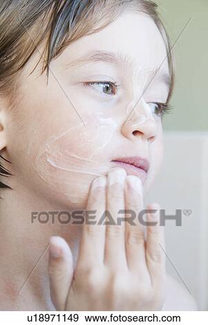 Girl rubbing moisturizer on her face View Large Photo Image Stock Photo - Girl rubbing moisturizer on her face. Fotosearch