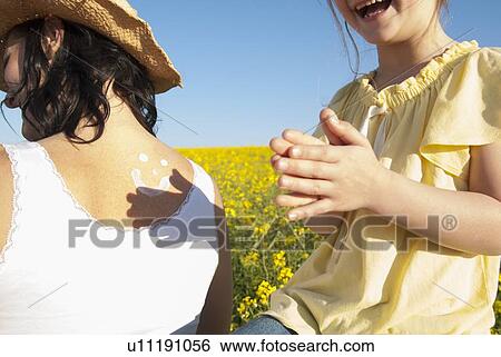 Girl rubbing sunscreen on mothers back View Large Photo Image Stock Photograph - Girl rubbing sunscreen on mothers back. Fotosearch