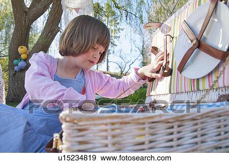 Stock Photo - Girl unpacking picnic basket outdoors. Fotosearch
