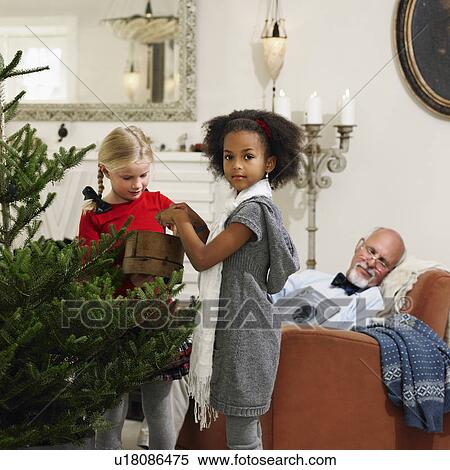 Stock Photography - Girls decorating Christmas tree. Fotosearch