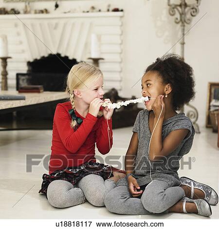 Stock Photo - Girls eating popcorn off string. Fotosearch