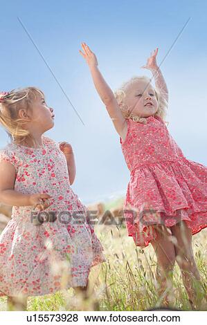 Stock Photo - Girls playing in tall grass. Fotosearch