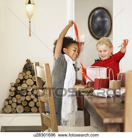 Stock Photograph - Girls wrapping Christmas presents. Fotosearch