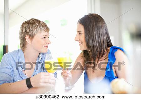 Stock Image - Lesbian couple having orange juice. Fotosearch