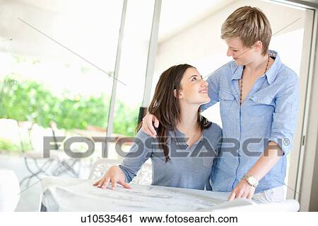 Stock Image - Lesbian couple reading blueprints. Fotosearch