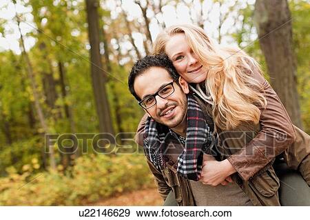Stock Photo - Man carrying girlfriend in forest. Fotosearch