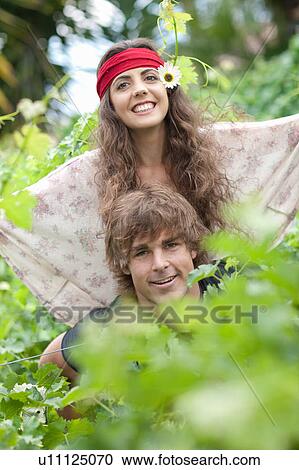 Stock Image - Man carrying girlfriend in tall plants. Fotosearch