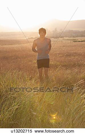 Stock Photography - Man jogging in tall grass. Fotosearch