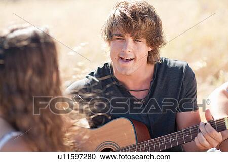 Stock Image - Man playing guitar for girlfriend. Fotosearch