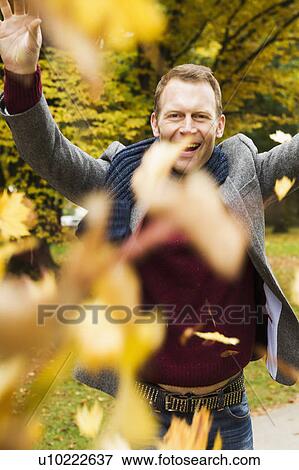 Man playing in autumn leaves View Large Photo Image Stock Photo - Man playing in autumn leaves. Fotosearch