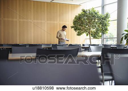 Man standing in empty cafeteria View Large Photo Image Stock Photo - Man standing in empty cafeteria. Fotosearch