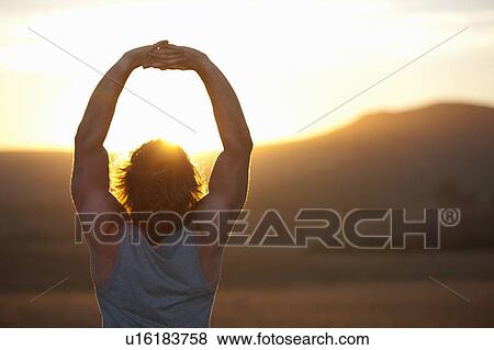 Man stretching in field at sunset View Large Photo Image Stock Photo - Man stretching in field at sunset. Fotosearch