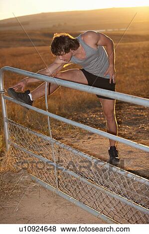 Man stretching on fence in rural field View Large Photo Image Stock Photo - Man stretching on fence in rural field. Fotosearch