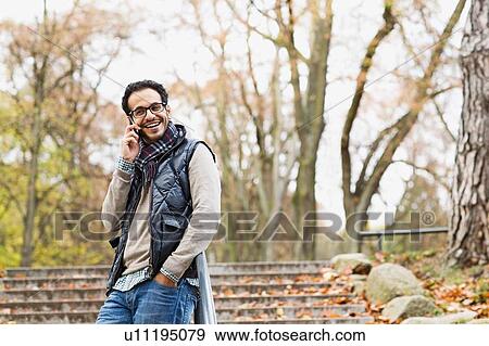 Man talking on cell phone in park View Large Photo Image Stock Photo - Man talking on cell phone in park. Fotosearch