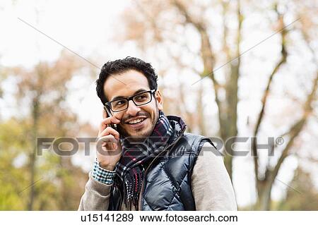 Man talking on cell phone in park View Large Photo Image Stock Photo - Man talking on cell phone in park. Fotosearch