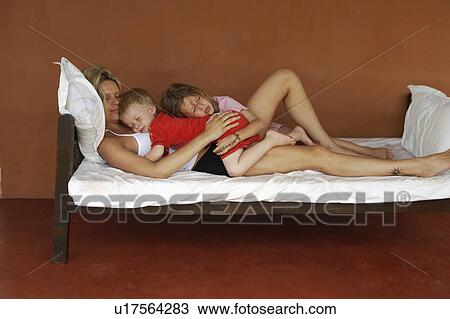 Stock Image - Mother and children sleeping on bed. Fotosearch