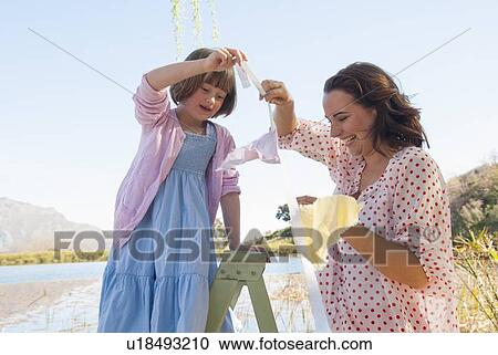 Stock Image - Mother and daughter hanging bunting. Fotosearch