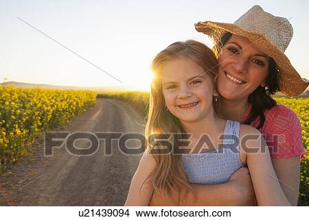 Picture - Mother and daughter hugging on dirt road. Fotosearch
