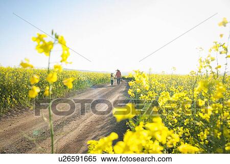 Stock Photography - Mother and daughter walking on dirt road. Fotosearch
