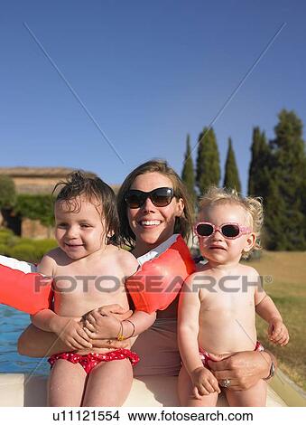 Picture - Mother holding daughters by pool. Fotosearch