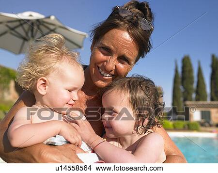 Picture - Mother holding daughters by pool. Fotosearch